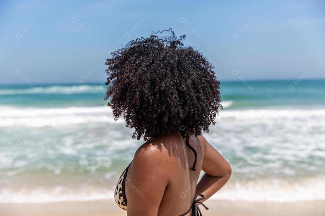 Afro morena jovem bonita, cabelo encaracolado, biquíni, praia. Férias de férias de verão