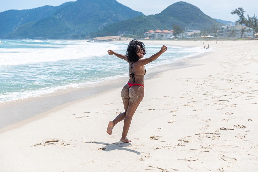 Afro morena jovem bonita, cabelo encaracolado, biquíni, praia. Férias de férias de verão
