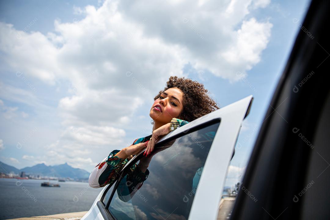 Linda garota afro-americana com um penteado afro sorrindo ao lado de um carro