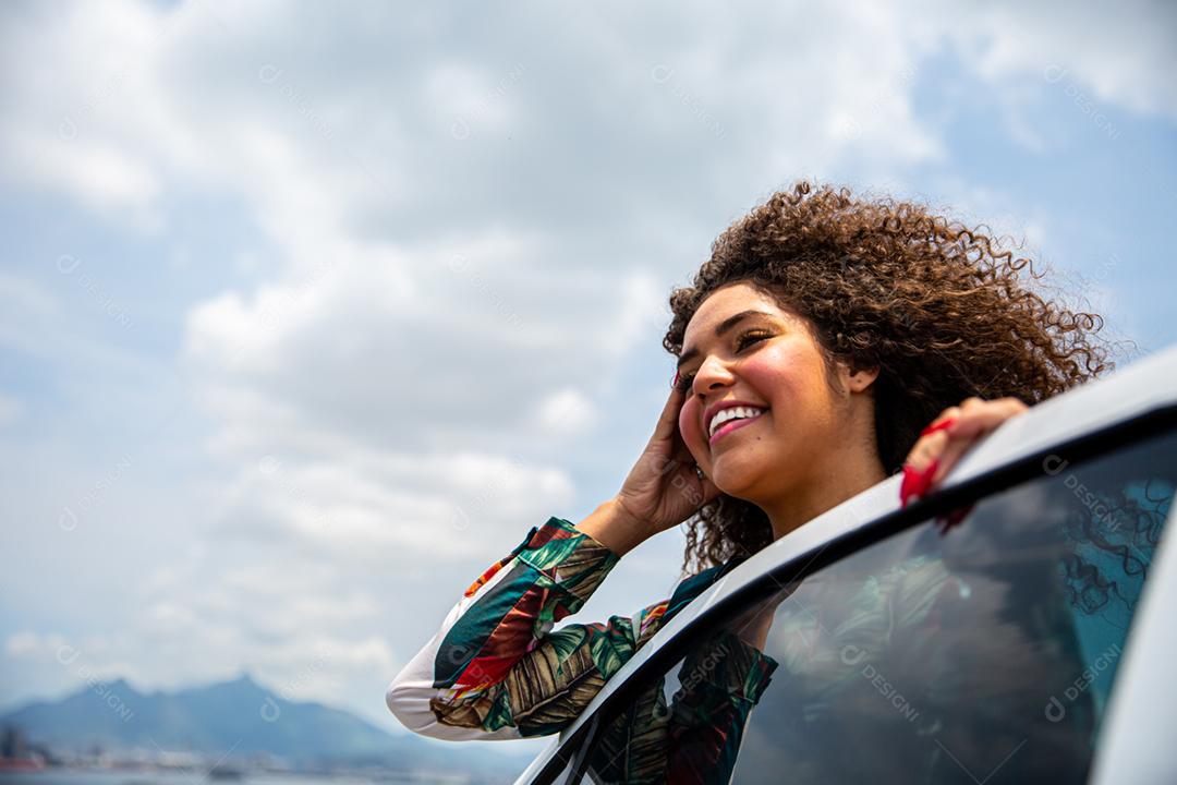 Linda garota afro-americana com um penteado afro sorrindo ao lado de um carro