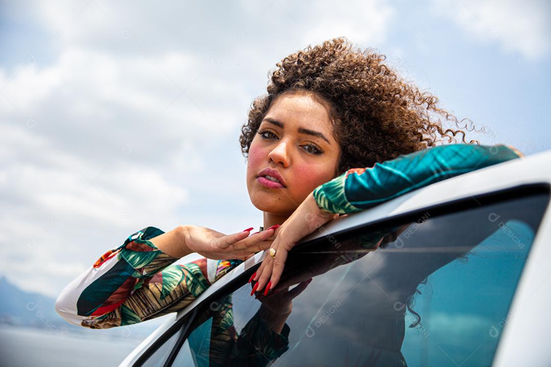 Linda garota afro-americana com um penteado afro sorrindo ao lado de um carro