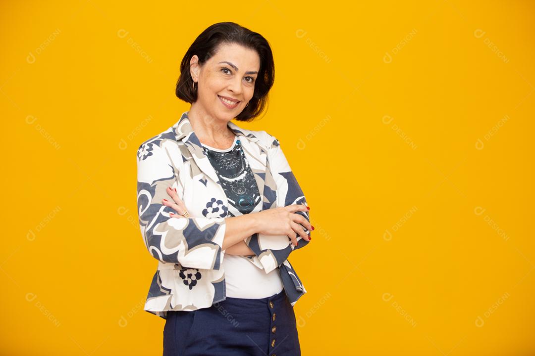 Mulher de meia idade atraente com belo sorriso na parede amarela. Mulher de negócios