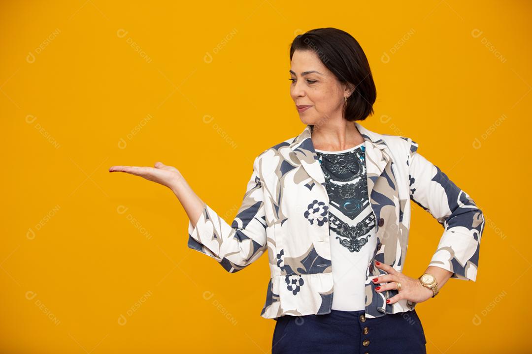 Beautiful middle aged business woman smiling and looking at camera pointing