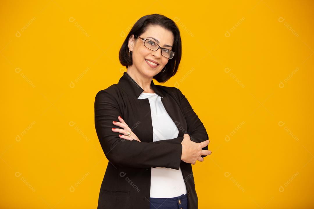 Mulher de meia idade atraente com belo sorriso na parede amarela. Mulher de negócios