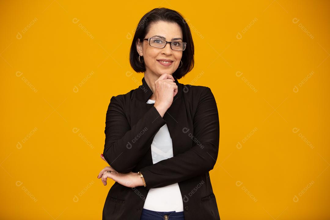 Mulher de meia idade atraente com belo sorriso na parede amarela. Mulher de negócios