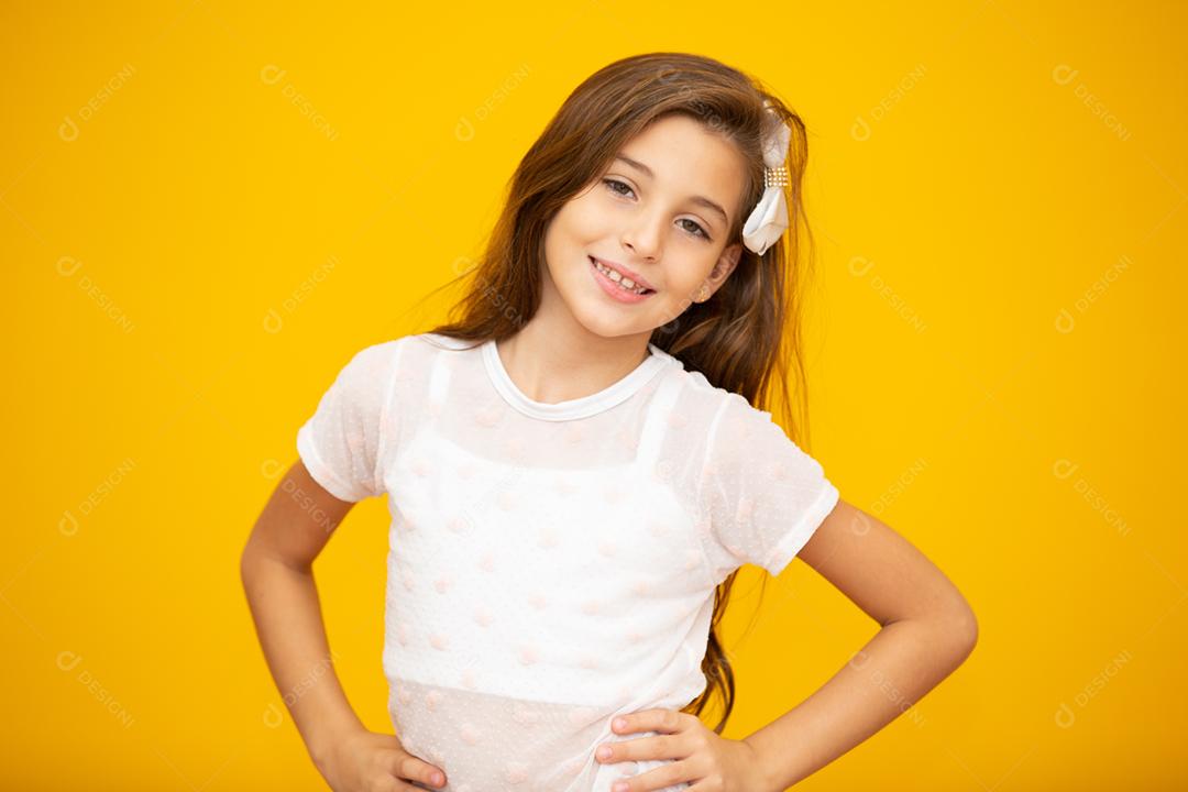 Retrato de uma menina criança sorridente feliz em fundo amarelo.