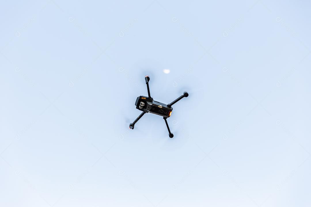 Black drone flying over clear sky