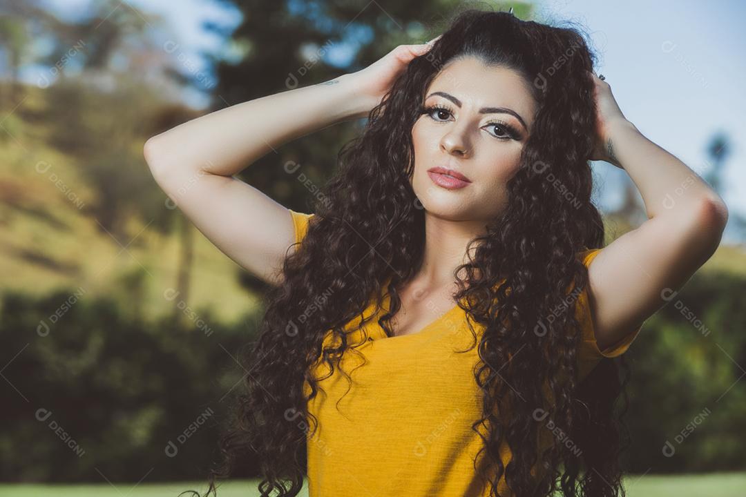 Mulher morena brasileira do cabelo cacheado da blusa amarela