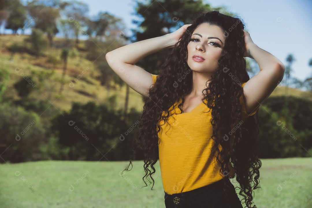 Mulher morena brasileira do cabelo cacheado da blusa amarela