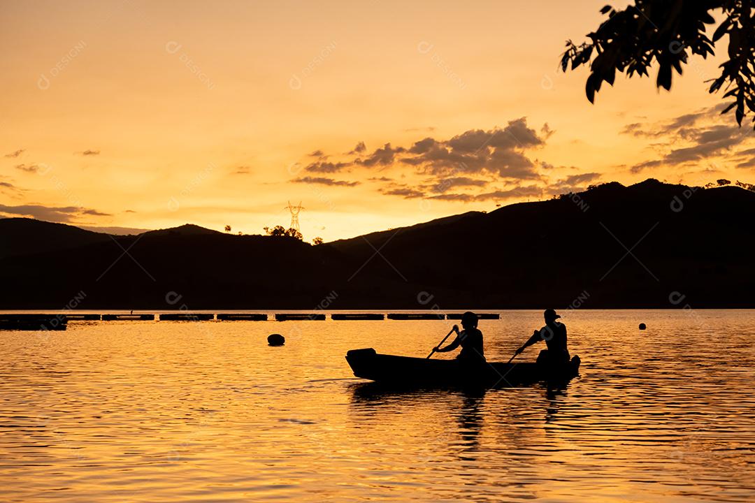 Por do sol. Tardezinha, pessoas remando canoa. Paisagem.