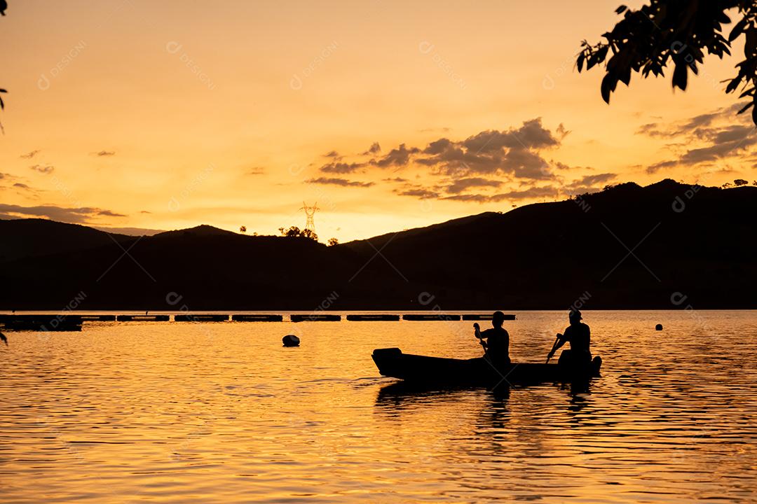 Por do sol. Tardezinha, pessoas remando canoa. Paisagem.