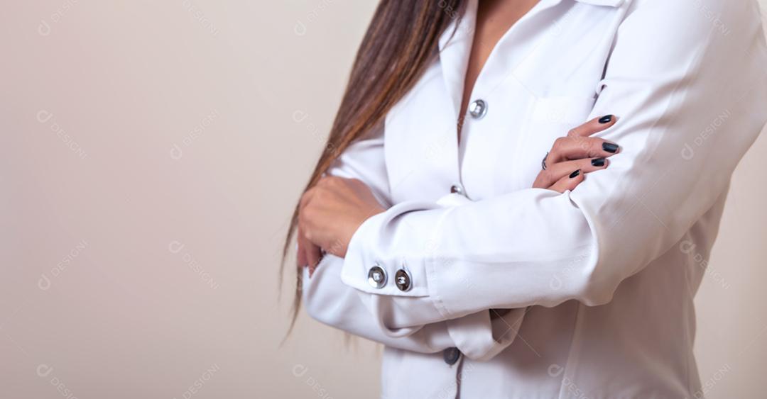 Mulher de médico de braços cruzados em um jaleco branco.