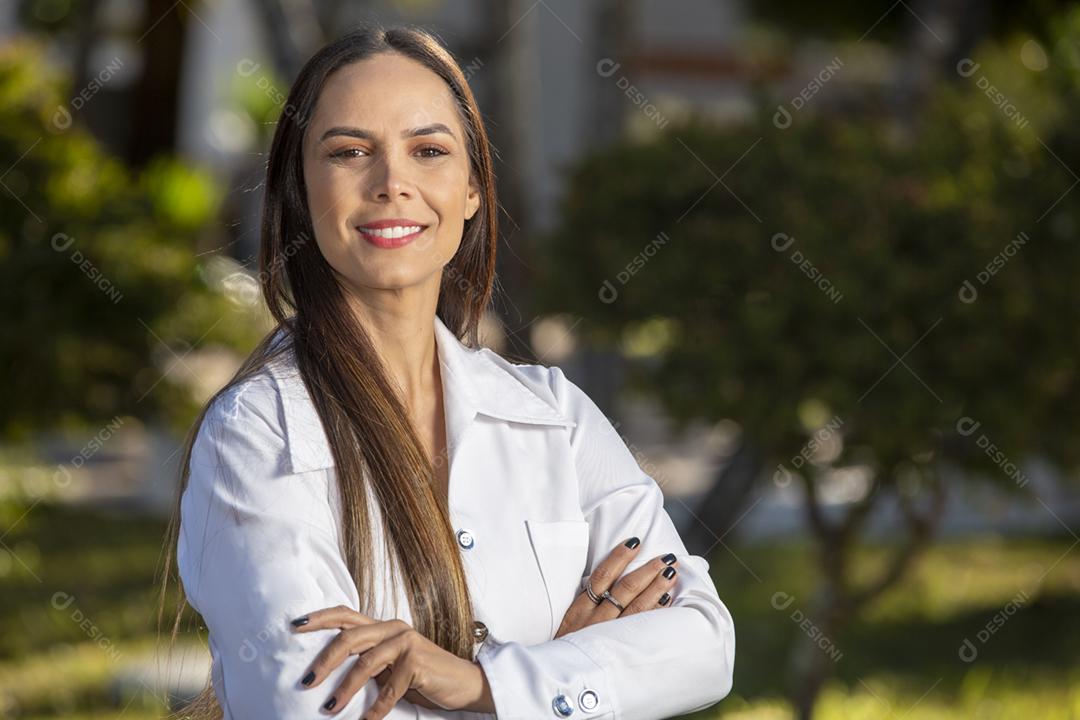 Mulher médica brasileira sorridente em um jaleco branco.