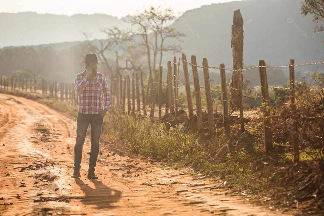 Agricultor ou homem do campo usando um smartphone na fazenda. Agricultor de Internet 4G
