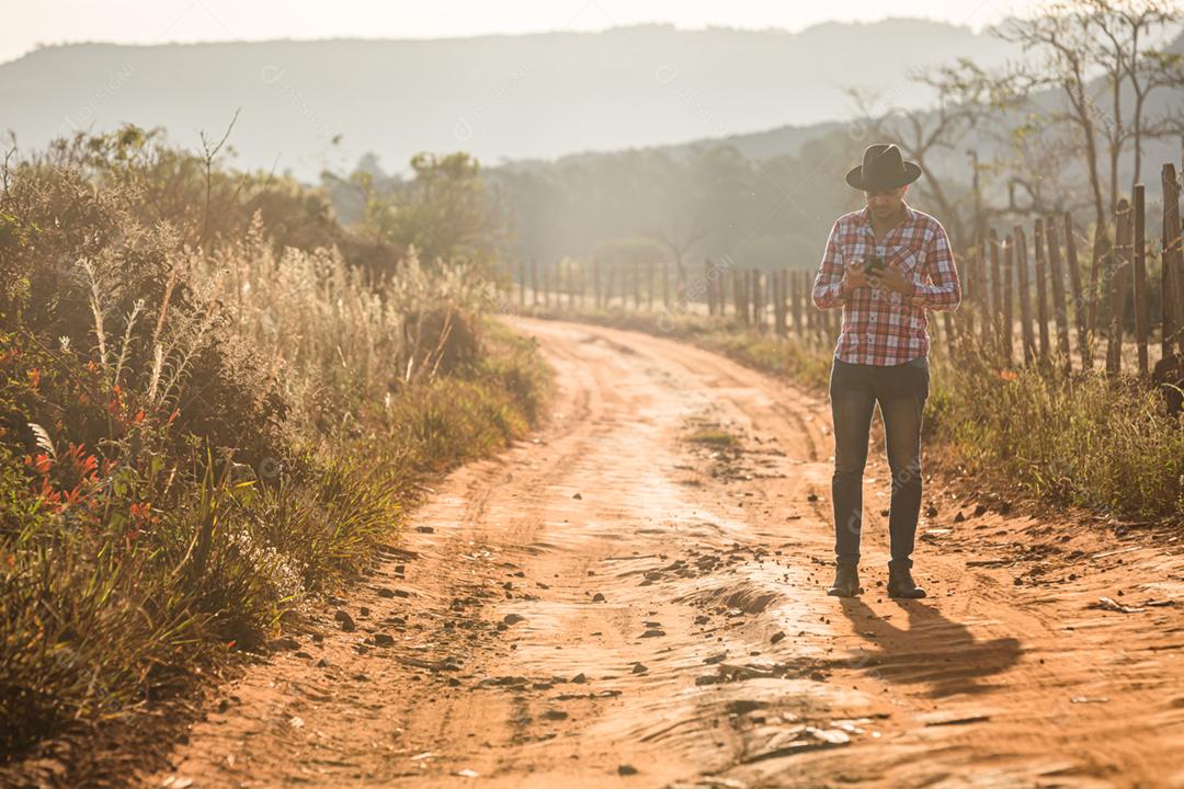 Agricultor ou homem do campo usando um smartphone na fazenda. Agricultor de Internet 4G