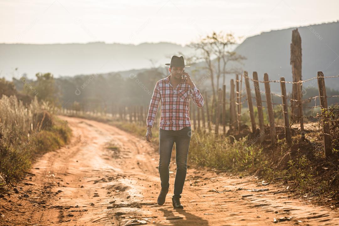 Agricultor ou homem do campo usando um smartphone na fazenda. Agricultor de Internet 4G