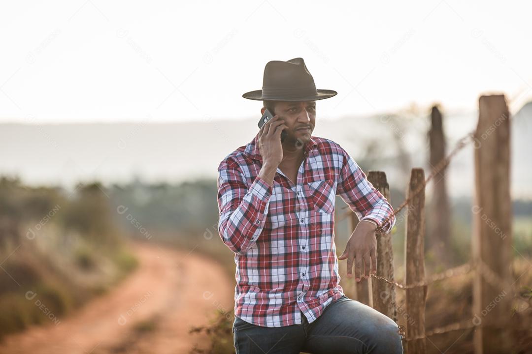 Agricultor ou homem do campo usando um smartphone na fazenda. Agricultor de Internet 4G