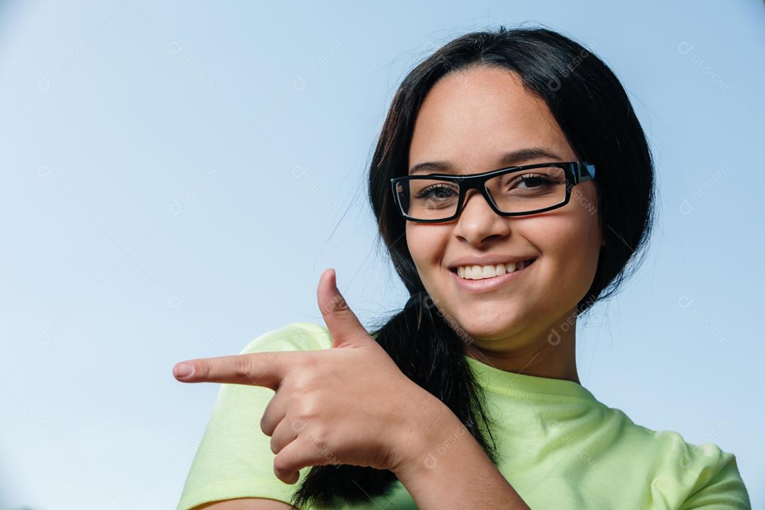 Jovem estudante morena de óculos olhando para a câmera e sorrindo.