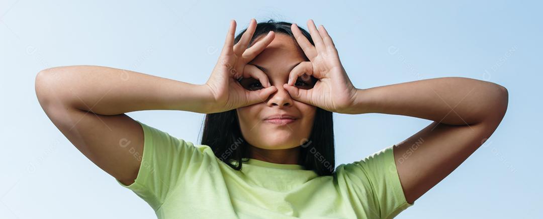 Feliz morena jovem fazendo sinal de óculos com as mãos.