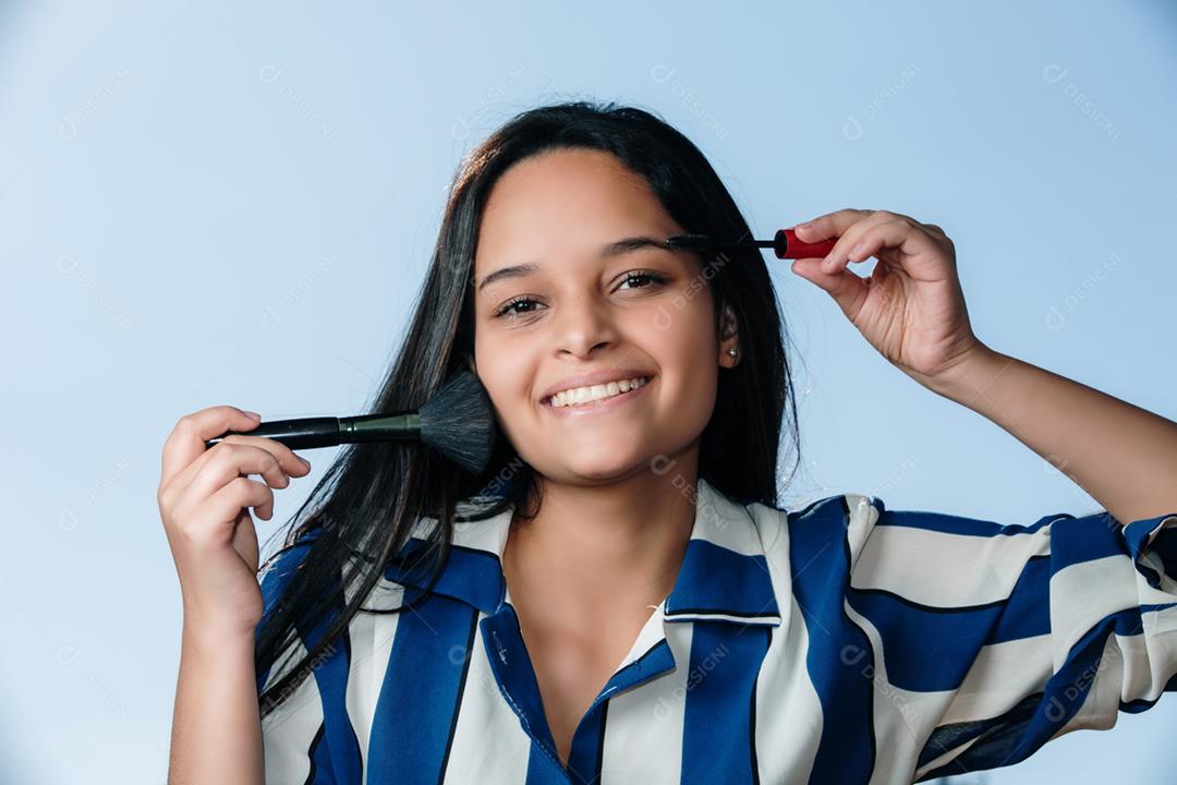 Feche de rosto mulher adolescente sorridente aplicando blush com pincel de maquiagem.