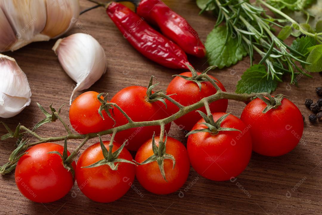 Tomate, alho, pimentão e ervas sobre a mesa de madeira.