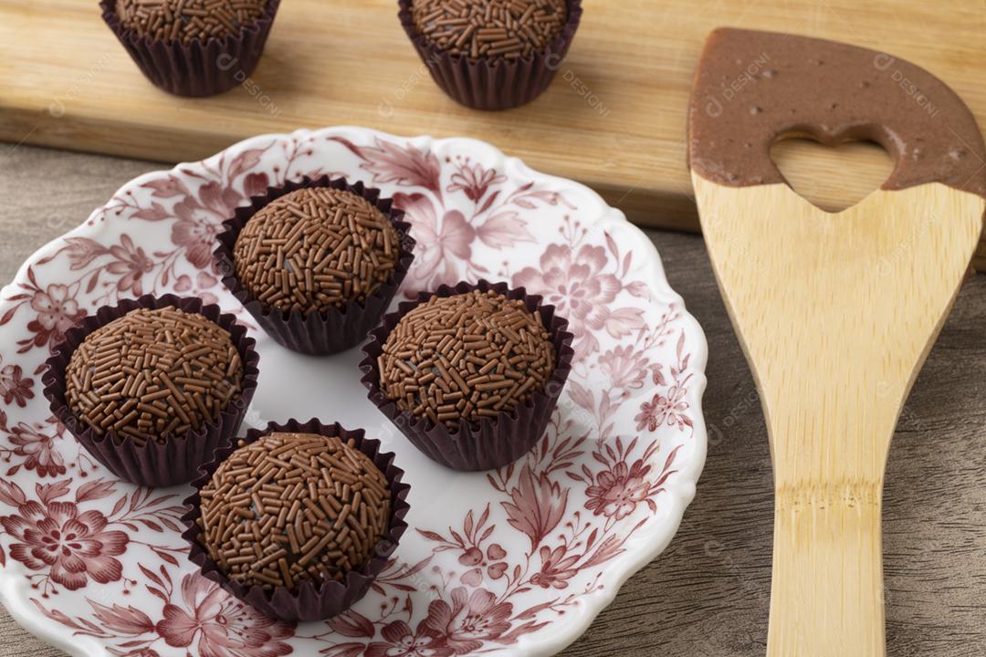 Brigadeiros brasileiros típicos com colher sobre a mesa de madeira.