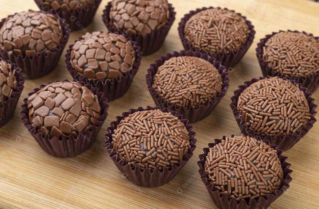 Brigadeiros típicos brasileiros, vários sabores sobre tábua de madeira.