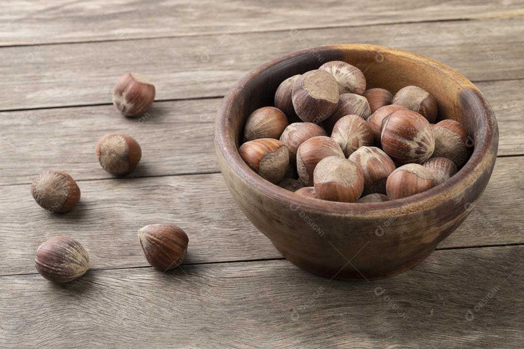 Um grupo de avelãs em uma tigela sobre a mesa de madeira.
