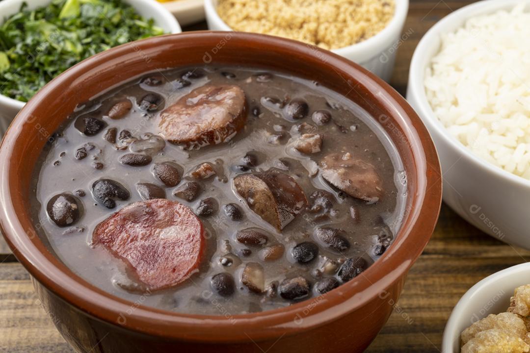 Feijoada tradicional brasileira com couve, pimenta, farinha de mandioca e caipirinha.