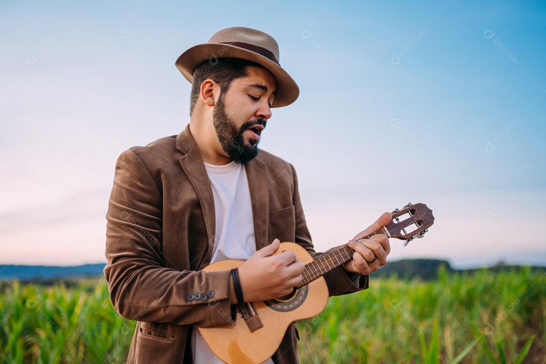 Ao ar livre de um jovem latino-americano tocando cavaquinho ou ukulele. músico brasileiro.