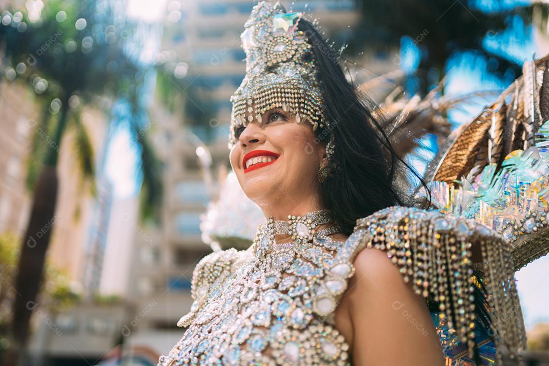 Beautiful Brazilian woman wearing colorful carnival costume and smiling during street parade