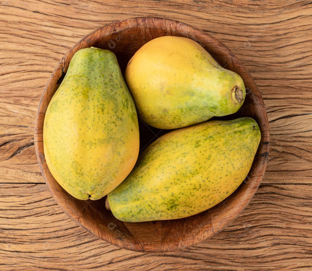 Mamão em uma tigela sobre a mesa de madeira.