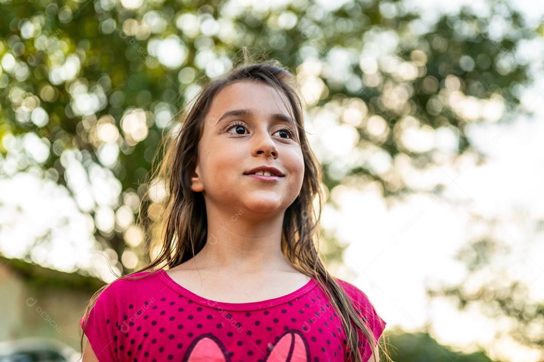 Menina criança bonita feliz sobre o fundo verde desfocado. Garoto na fazenda. Povo latino.