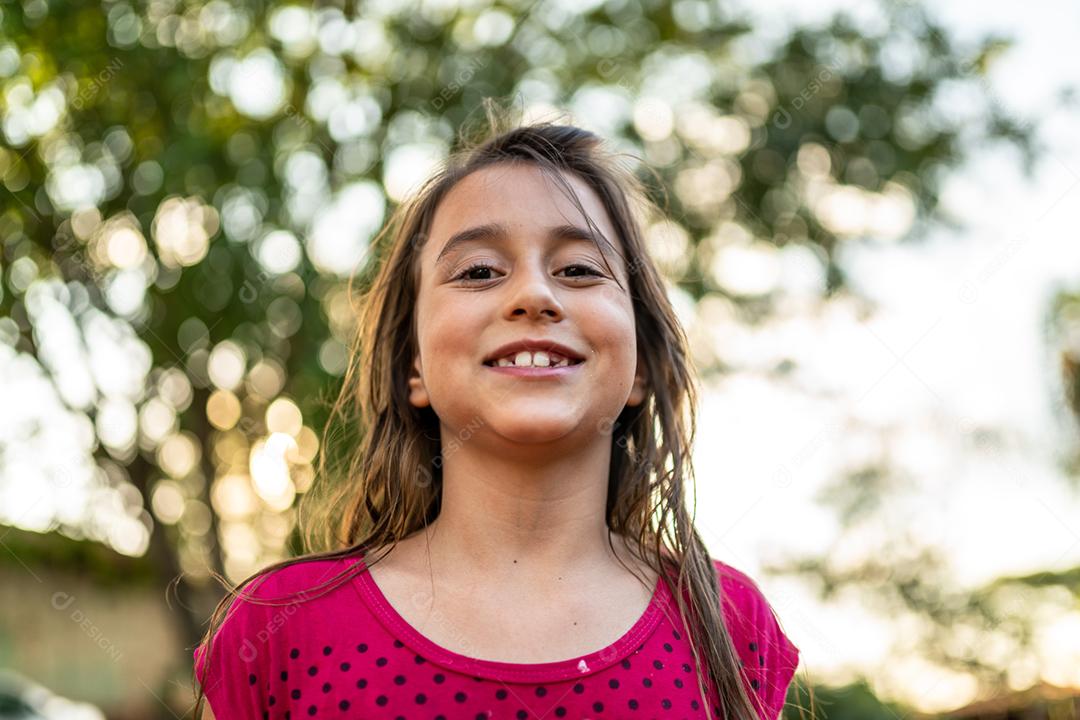 Menina criança bonita feliz sobre o fundo verde desfocado. Garoto na fazenda. Povo latino.