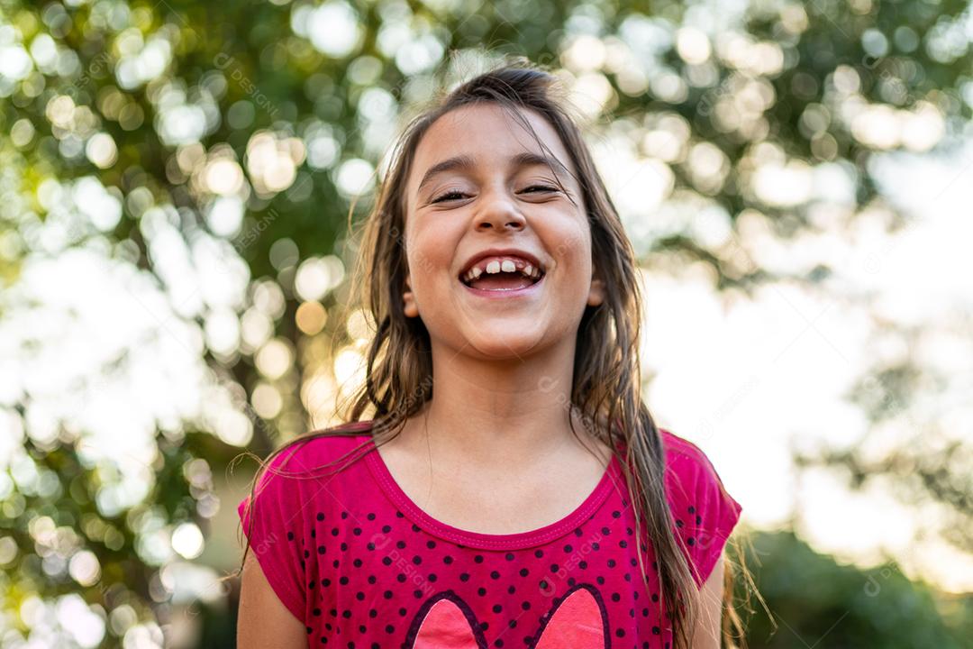 Menina criança bonita feliz sobre o fundo verde desfocado. Garoto na fazenda. Povo latino.