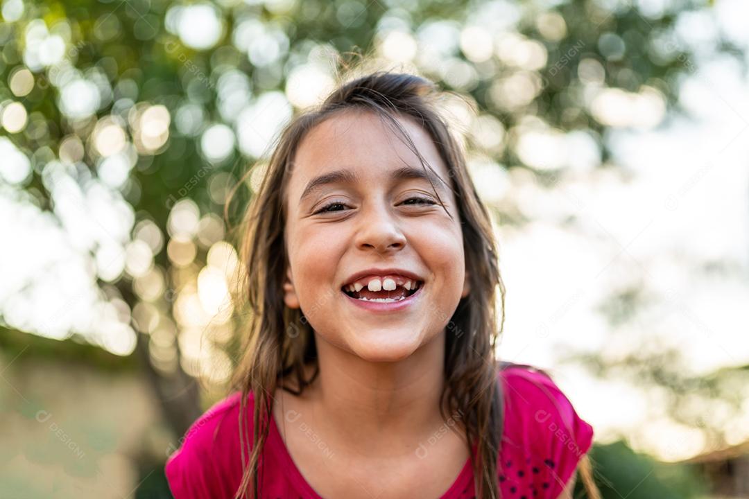 Menina criança bonita feliz sobre o fundo verde desfocado. Garoto na fazenda. Povo latino.