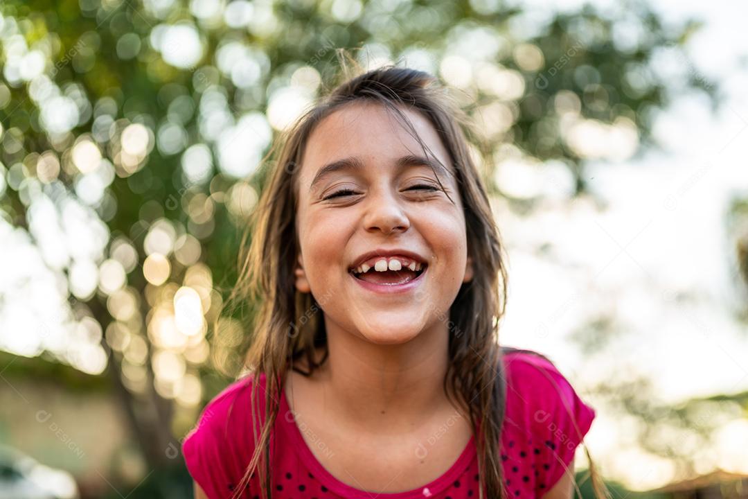 Menina criança bonita feliz sobre o fundo verde desfocado. Garoto na fazenda. Povo latino.