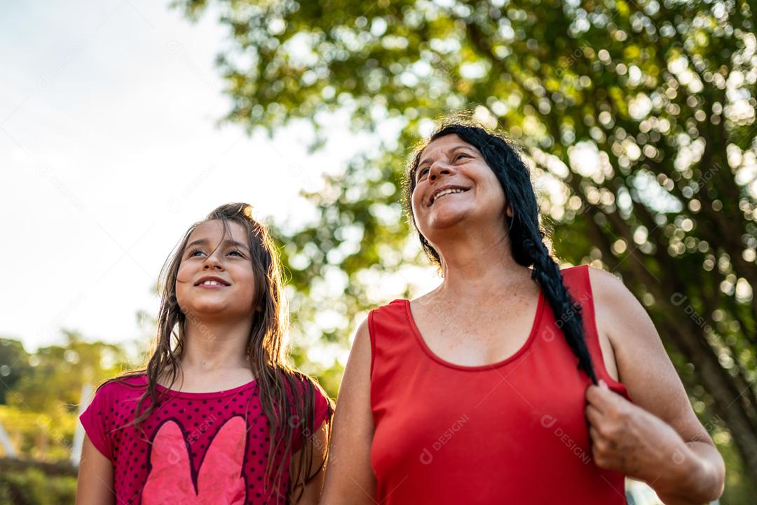 Menina criança bonita feliz avó desfoque de fundo verde Criança e avó fazenda. família latina.
