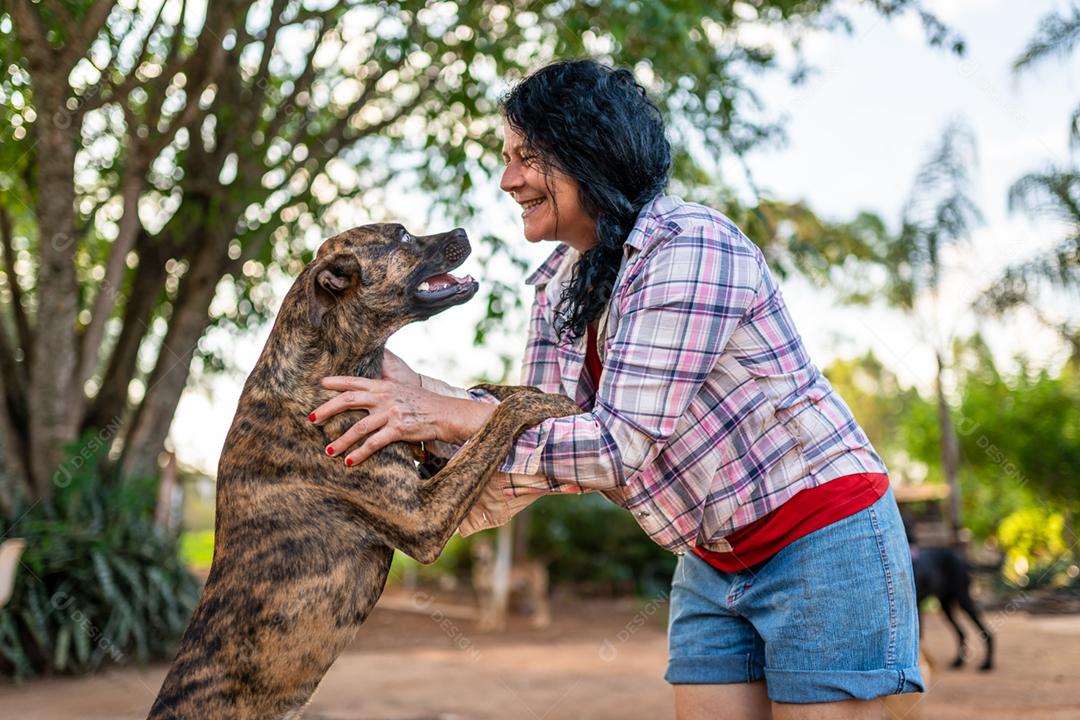 Retrato de sorrindo linda agricultora com um cachorro. Mulher na fazenda em dia de verão
