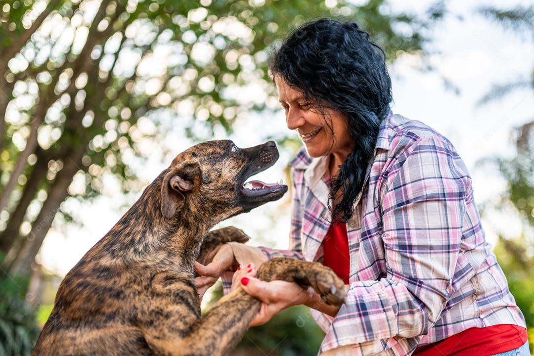 Retrato de sorrindo linda agricultora com um cachorro. Mulher na fazenda em dia de verão