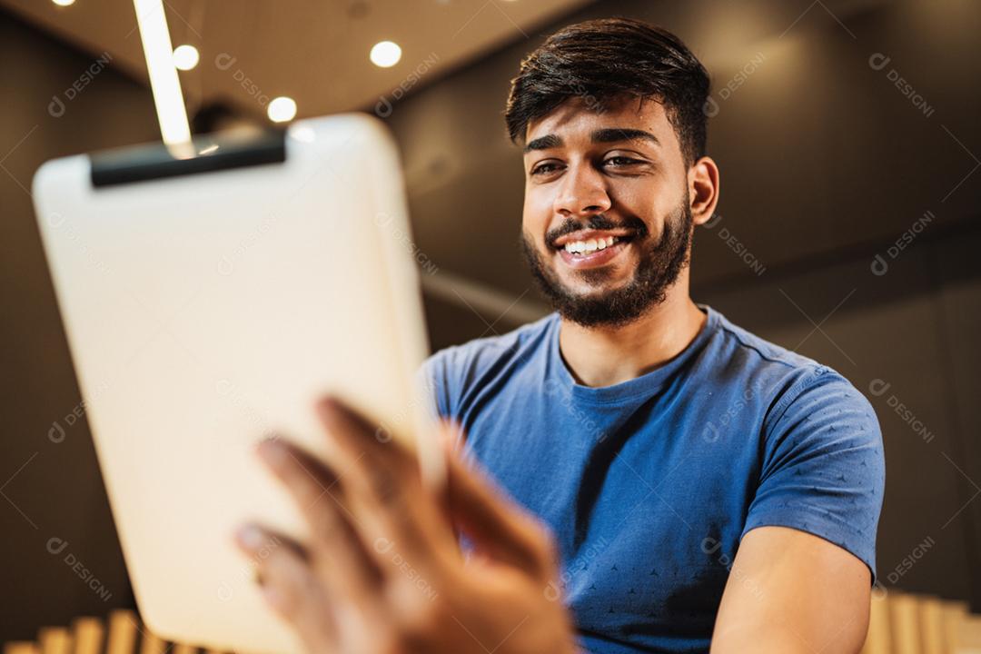 Jovem latino usando tablet digital. Mensagens de texto no café.