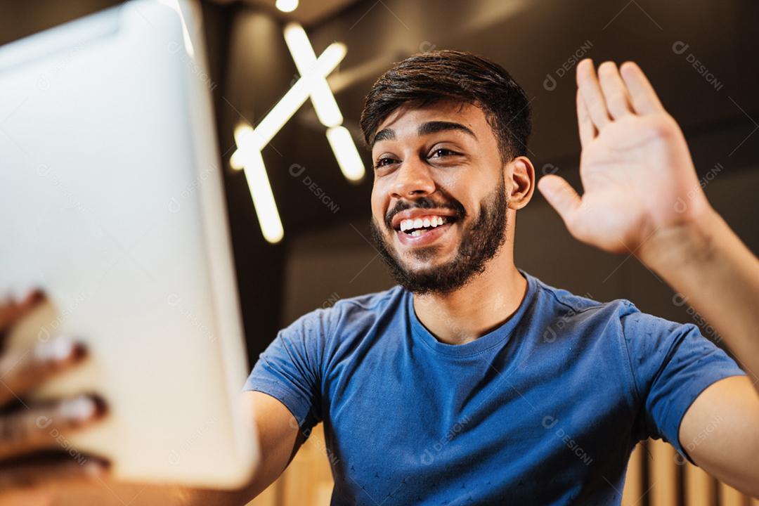 Jovem latino fazendo uma chamada de vídeo no café.