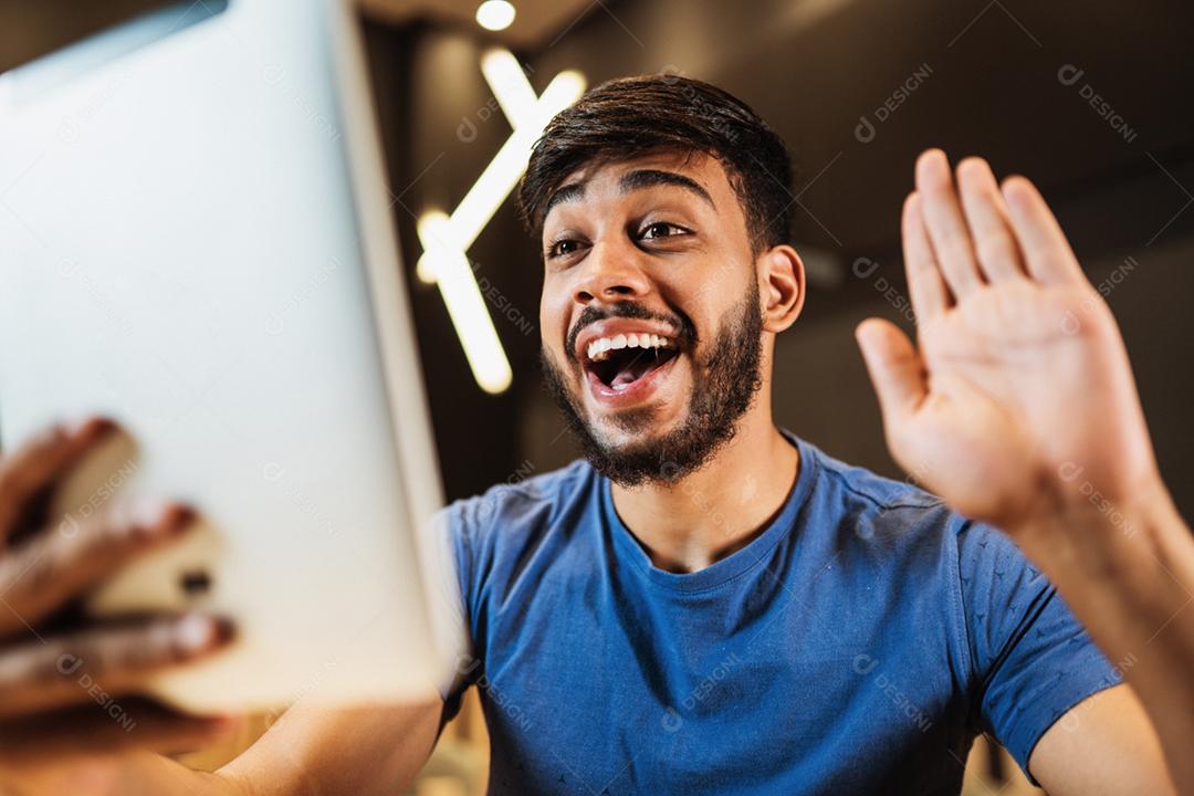 Jovem latino fazendo uma chamada de vídeo no café.