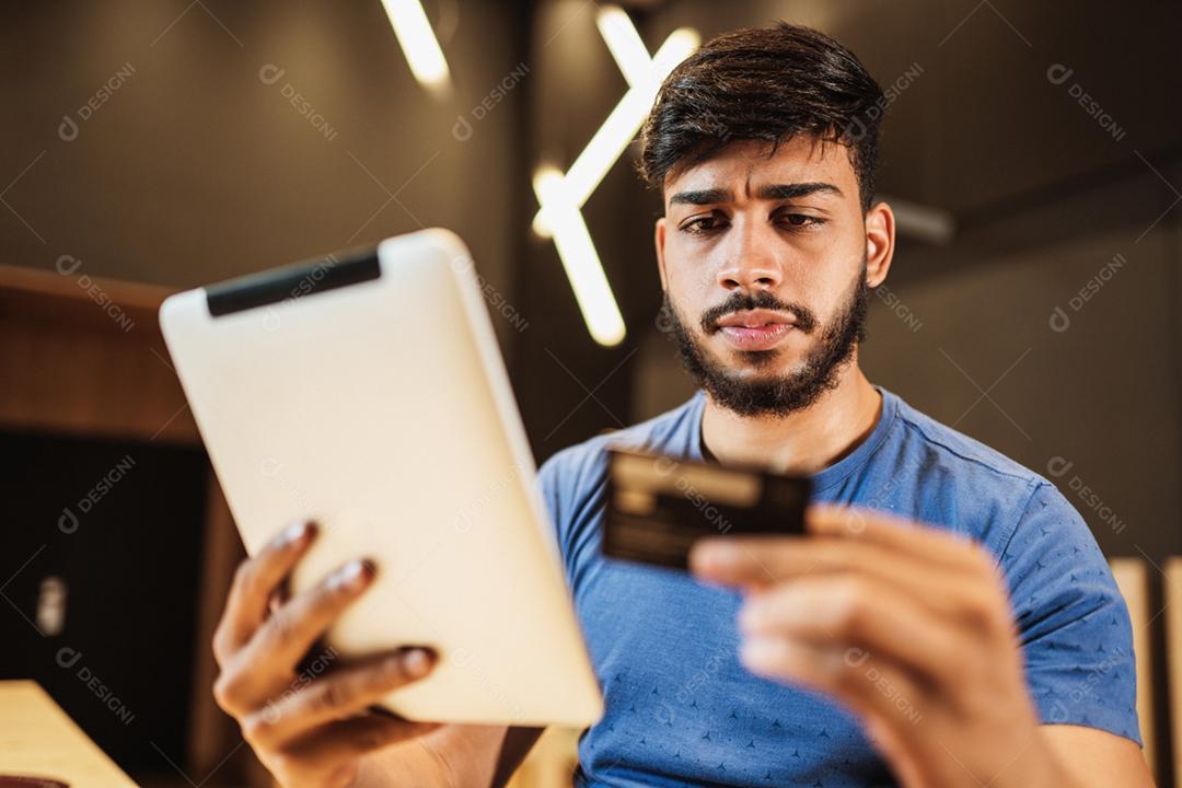 Jovem latino usando tablet digital. Mensagens de texto no café.