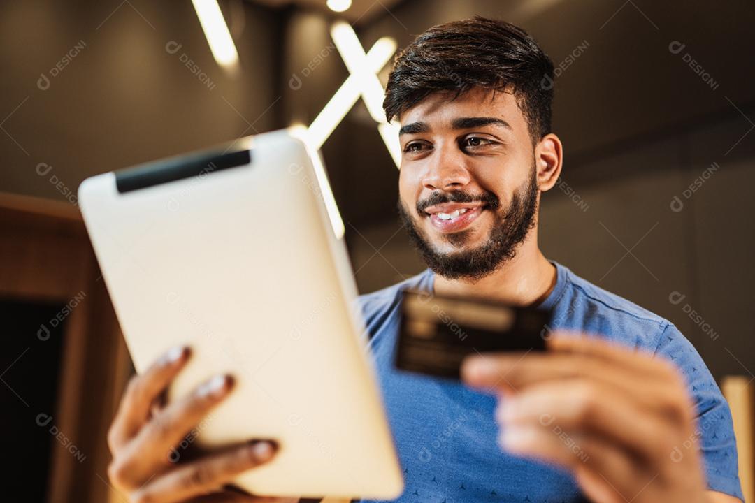 Jovem latino usando tablet digital. Mensagens de texto no café.