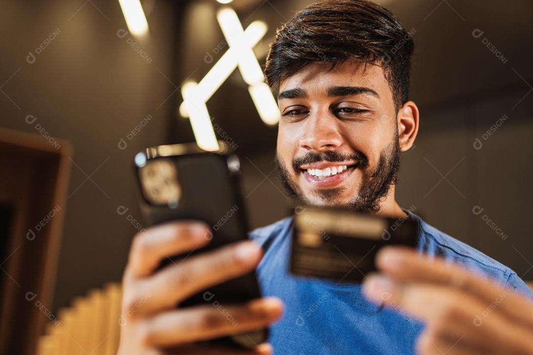 Jovem latino usando smartphone digital. Mensagens de texto no café.