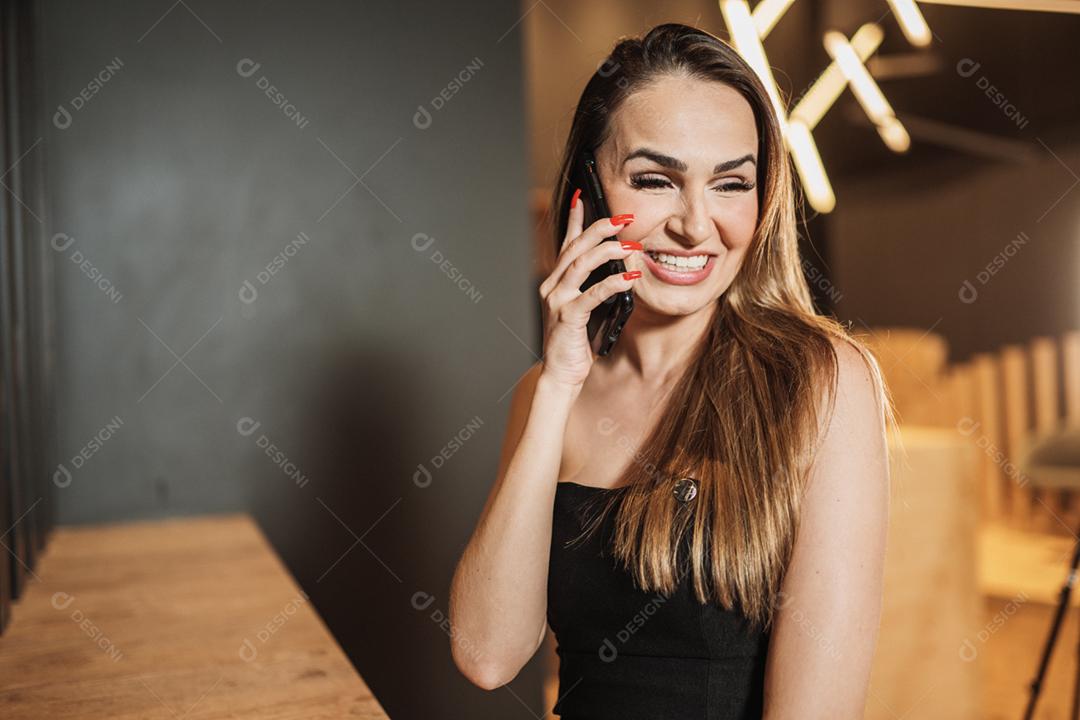 Jovem mulher latina no café falando ao telefone.