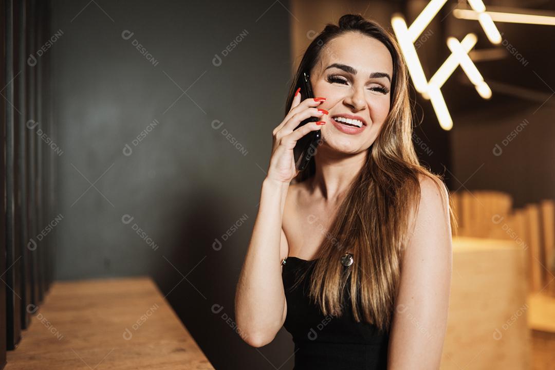 Jovem mulher latina no café falando ao telefone.