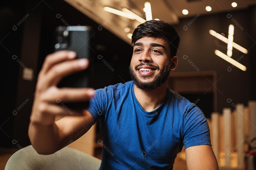 Feliz jovem latino fazendo selfie no smartphone.