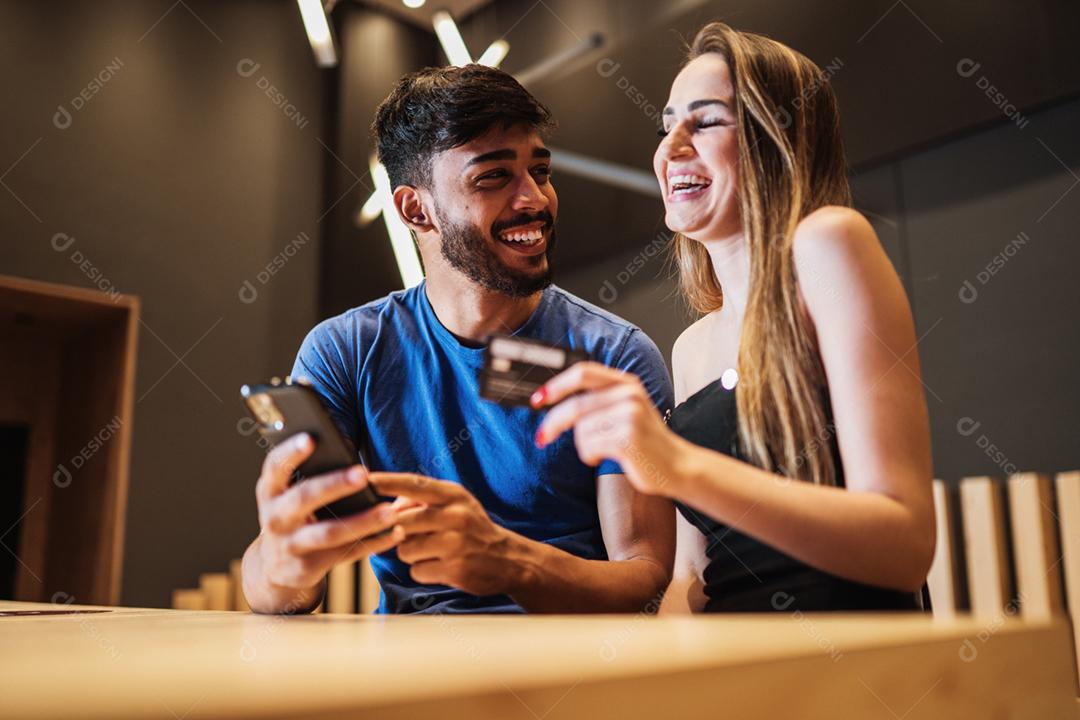 Banco online jovem casal usando smartphone fazendo compras online com cartão de crédito